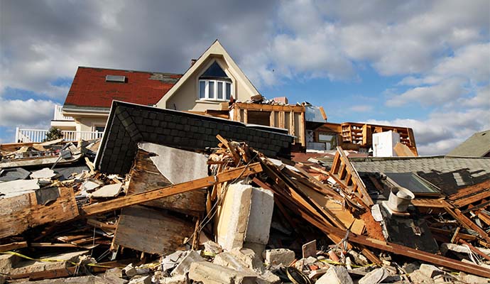 A storm-damaged house with a collapsed roof and walls.