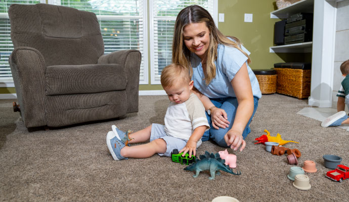 a woman and child playing on a carpeted floor